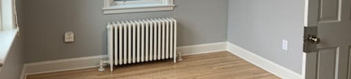 A room with a window and a radiator on the floor.