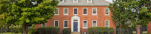 A red brick house with a black fence in front.