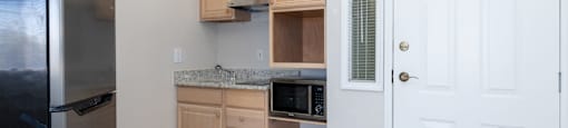 A kitchen with a black fridge, white door, and wooden cabinets.