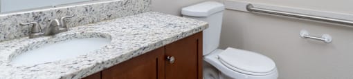 A bathroom with a marble countertop and white fixtures.