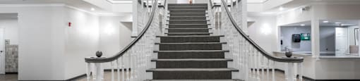 A staircase with a carpeted landing and white railings.