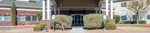 A building with a covered entrance and a parking lot in front.