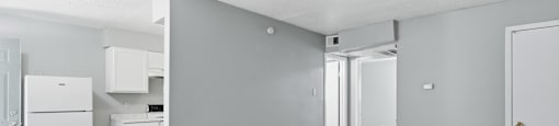A kitchen area with a white refrigerator and a grey wall.