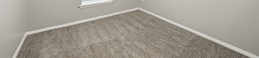 A room with a carpeted floor and a window.