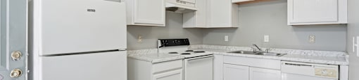 A white kitchen with a refrigerator, oven, and sink.