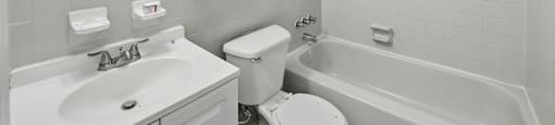 A white bathroom with a toilet, sink, and bathtub.