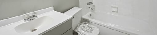 A white bathroom with a toilet, sink, and bathtub.