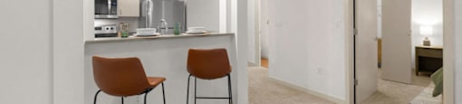 a kitchen and bar with two stools in a living room
