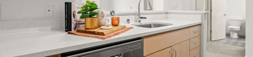 A modern kitchen with wooden cabinets and a stainless steel dishwasher.