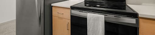 A kitchen with a stainless steel refrigerator, black stove, and microwave above it.