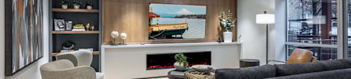 A modern living room with a grey couch, a white fireplace, and a painting on the wall.