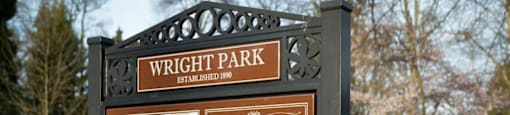 a man walks his dog past a wright park sign