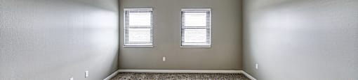 A room with a ceiling fan and two windows.