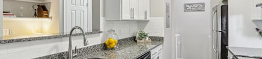 A kitchen with granite countertops and white cabinets.