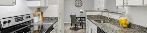 A kitchen with white cabinets and a granite countertop.
