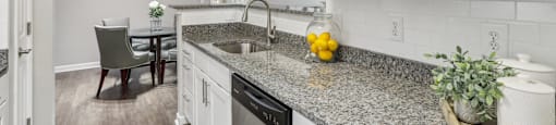 A kitchen with granite countertops and white cabinets.