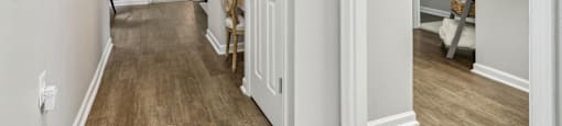 A hallway with a wooden floor and white walls.