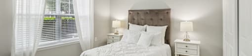 A bedroom with a large bed, two nightstands, and a window with curtains.