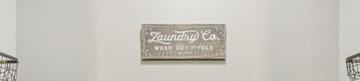 Two white washing machines in front of a sign that says "Tauntry Co. Wash Dry Fold".