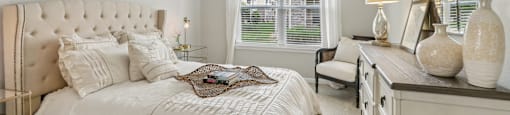 A bedroom with a large bed, a nightstand, and a window with curtains.