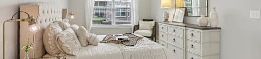 A bedroom with a large bed, a dresser, and a mirror.