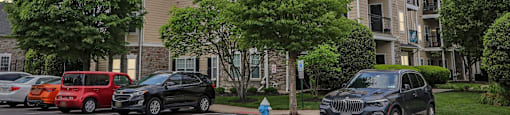 A black car is parked in a parking lot in front of a building.
