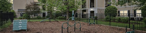 A playground with a swing set and a slide in front of apartment buildings.