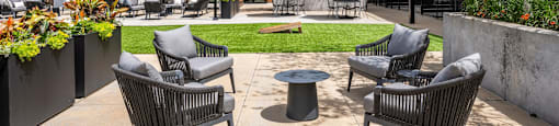 A patio with chairs and tables is surrounded by a building.