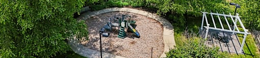 A playground surrounded by trees with a swing set.