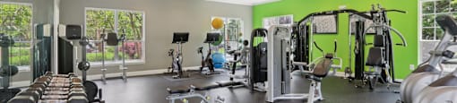 A gym with a variety of equipment including treadmills, weights, and exercise machines.