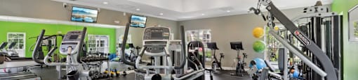 A gym with a variety of equipment including treadmills, stationary bikes, and weight machines.