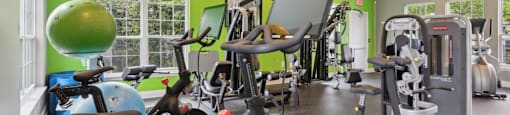 A gym with a variety of exercise equipment including treadmills, stationary bikes, and weight machines.