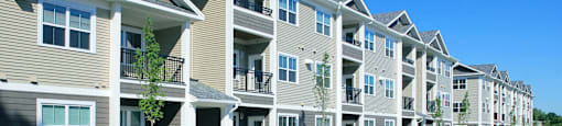 A row of modern apartment buildings with cars parked in front.
