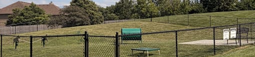 A park with a green bench and a fence.
