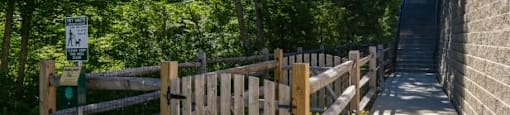 A wooden fence and gate lead to a pathway in a park.