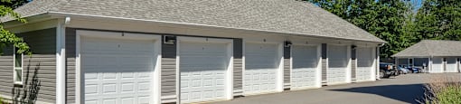 A building with a grey roof and white garage doors.