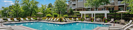 A large swimming pool surrounded by sun loungers and umbrellas.