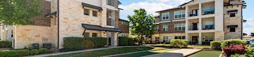 A modern apartment complex with a well-maintained lawn and landscaping.