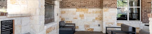 A modern outdoor seating area with a stone wall and wooden ceiling.