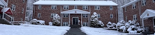 A snow-covered pathway leads to a brick building with a covered entrance.