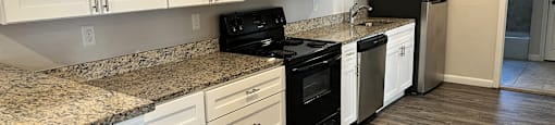 A kitchen with white cabinets and a granite countertop.