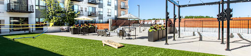 A modern apartment complex with a green lawn and a playground.