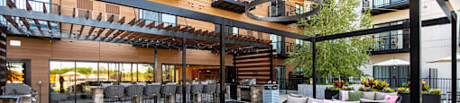 A patio area with black metal furniture and a black metal pergola.