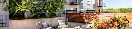 A patio with chairs and a table with a view of a building.