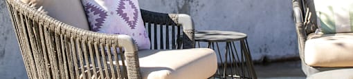 A patio with a chair and a table with a cushion on it.
