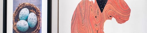 A wall with a painting of a bird and a painting of a woman.