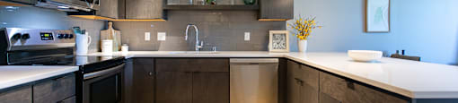 A modern kitchen with dark wood cabinets and stainless steel appliances.
