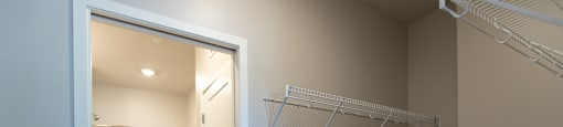 A white closet with a white door and a white curtain in the other room.
