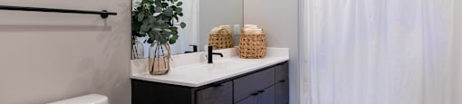 A bathroom with a white toilet, a white sink, and a white shower curtain.