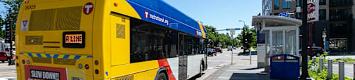 A yellow bus with a blue roof is on a city street.